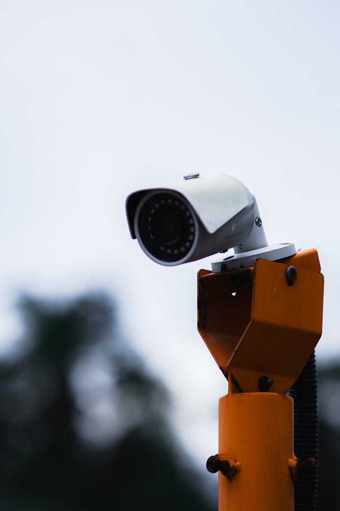 our-story A security camera mounted on an orange stand against a blue sky.